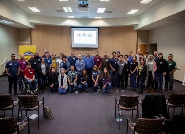 Over two dozen students and panelists stand alongside one another for a picture after a professional development event in Fresno, CA.
