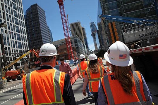 Group walking near construction site with hardhats