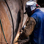 Worker welding giant pipe.