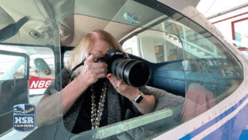 woman sitting in small airplane holding camera with telephoto lens, BuildHSR California logo 
