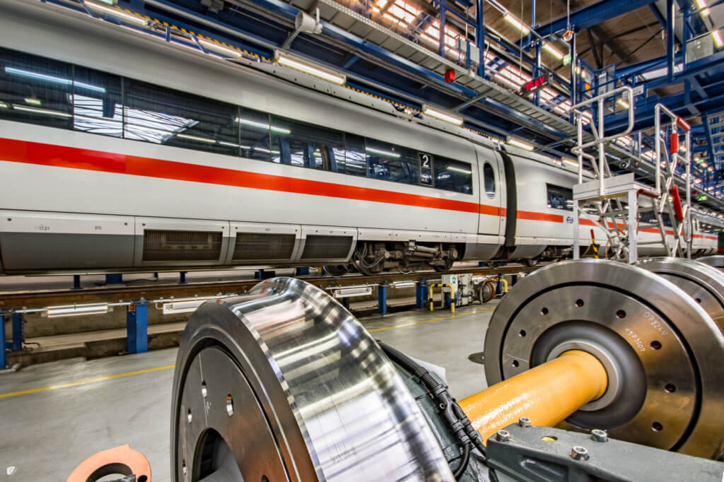 High-speed rail passenger cars are suspended in a frame with wheels separate in foreground
