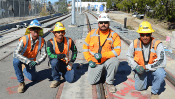 Four construction workers kneeling on train tracks