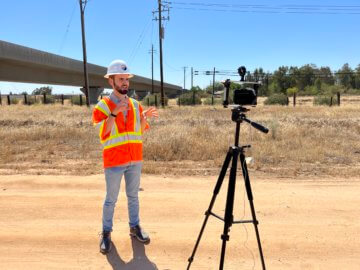 Person in protective construction equipment speaking in front of a camera. 
