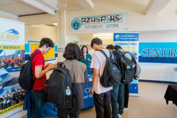 group of students standing at high-speed rail outreach table in front of Azusa HS Student Store