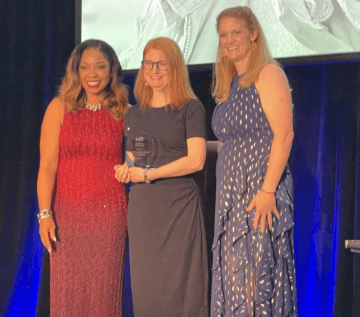 Photo of women standing on stage with Award 