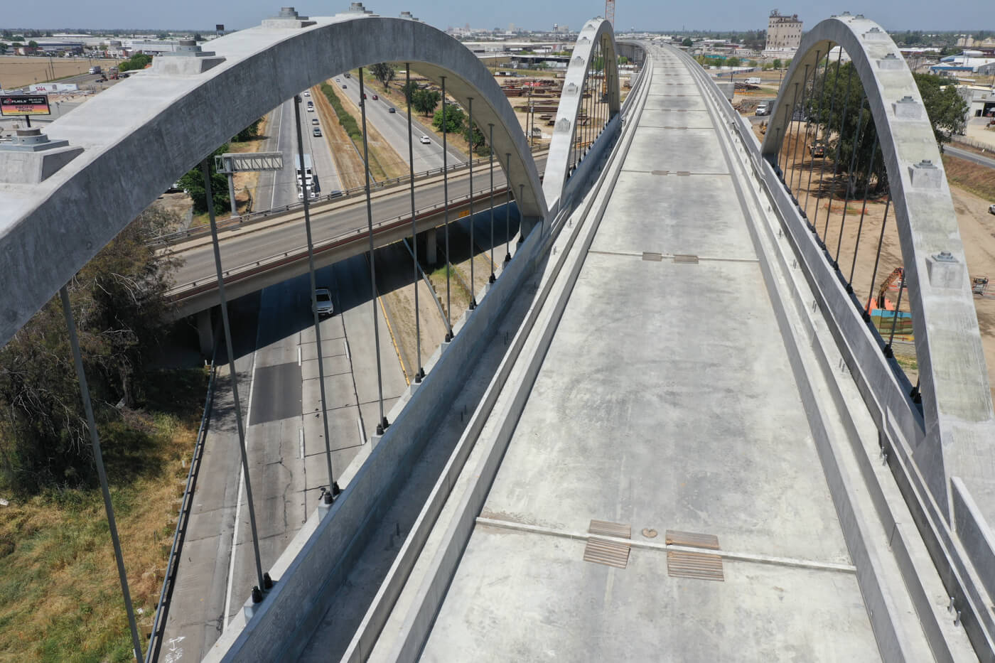 Concrete bridge above a freeway. The bridge has 3 concrete arches. 