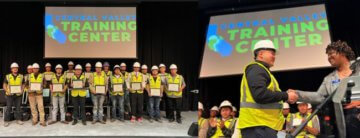 Picture includes 17 pre-apprentice graduates who completed program. They are standing on stage holding their certificates in front of them. Logo of Central Valley Training Center is projected behind them on screen and Picture of woman and man shaking hands on stage. Group of graduates are sitting behind them under sign that says: Central Valley Training Center.