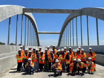 Large group of students in construction vests and hard hats atop the San Joaquin River Viaduct.