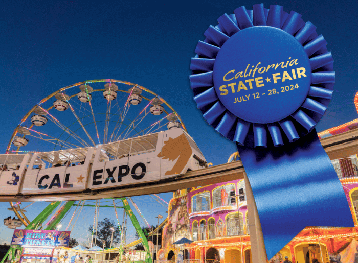 Farris wheel in background with rail cars in front displaying Cal Expo and blue ribbon that says California State Fair July 12 to 28.