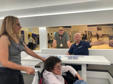 Visitors touring the family area of white mock-up trainset interior while talking to Authority staff.