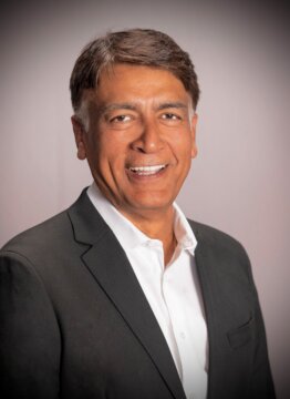 Headshot of Ian Choudri in a gray suit and white-button up shirt.