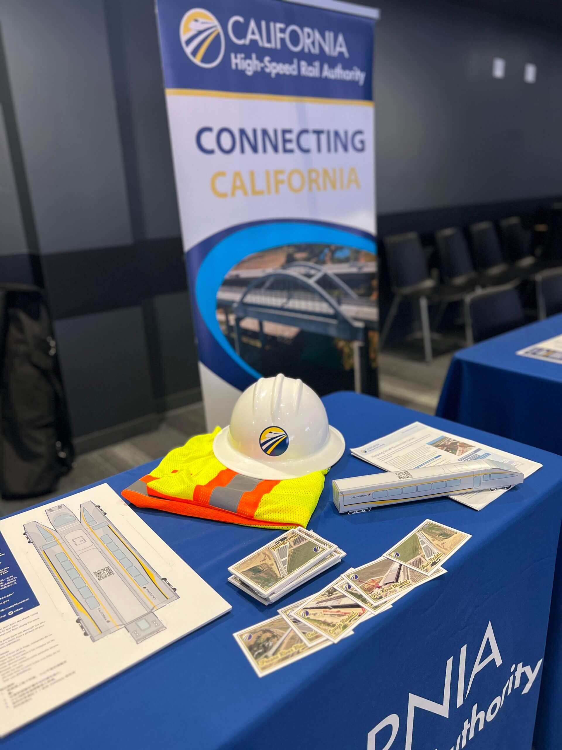 Picture of information table, with literature, a pop up banner, and a hard hat visible.