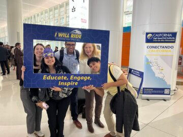 5 attendees pose with ‘I Will Ride’ frame. 