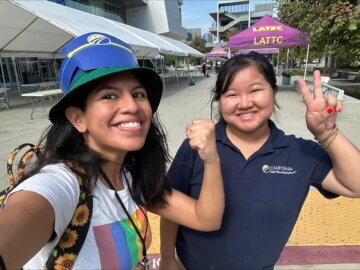 Two people smiling and showing peace signs while taking a selfie. 