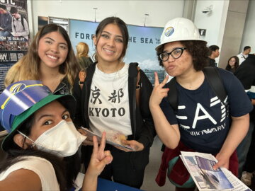 Authority staff member taking a selfie and smiling with three students at an outreach event. 