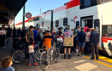 A crowd of riders boards a new electric Caltrain car in San Mateo, California.