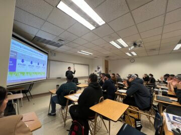 Authority Director of Sustainability and Station Planning Meg Cederoth stands in front of a classroom of students and presents on a high-speed rail sustainability topic.