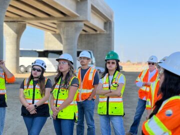 Alt txt: Students stand at a construction site and learn about the viaduct structure.