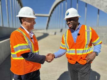 CEO Ian Choudri and California’s Transportation Secretary Toks Omishakin on a construction site shaking hands and smiling. 