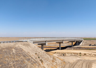 Taken from above via drone, the Avenue 88 Grade Separation predominates the photo, taking center stage. Parched earth surrounds it on all sides, as it passes over State Route 43 and the BNSF freight railroad tracks below, as well as the eventual location of high-speed rail tracks. A cloudless and bright sky meets the horizon taking up about half the photo.